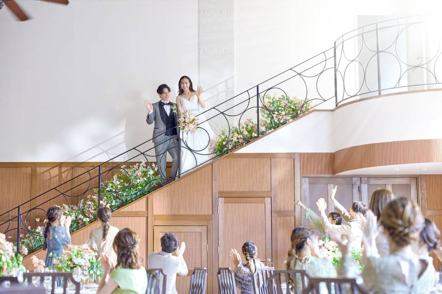 階段からゲストに手を振る新郎新婦